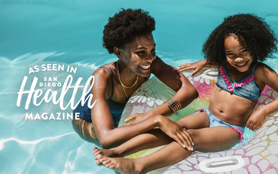 A mother and her daughter playing in the pool and smiling enjoying the Summer fun.