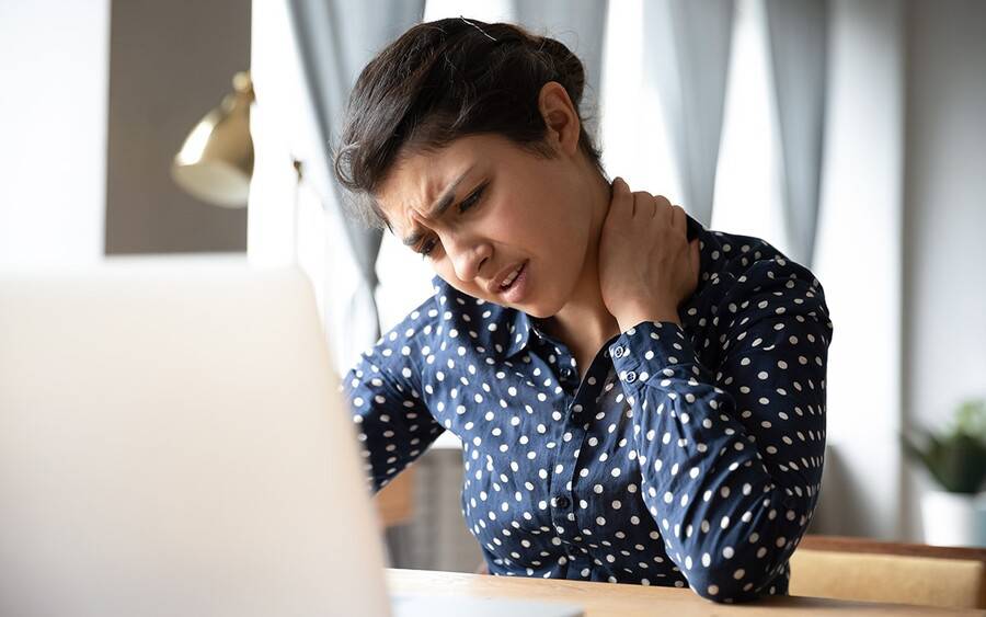 Young woman grabs her neck and winces in pain.