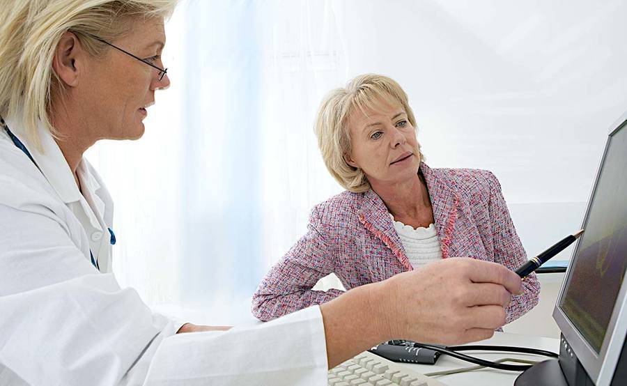 A doctor points to a computer screen while talking with her patient, representing the high-tech approach to neurointerventional surgery at Scripps.