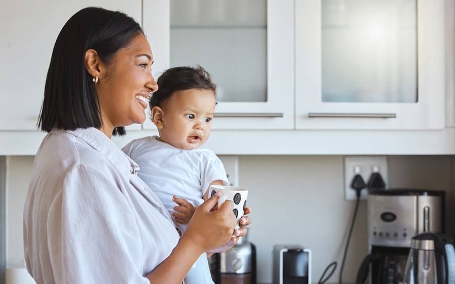 A smiling new mom holds her baby. Postpartum health is important.