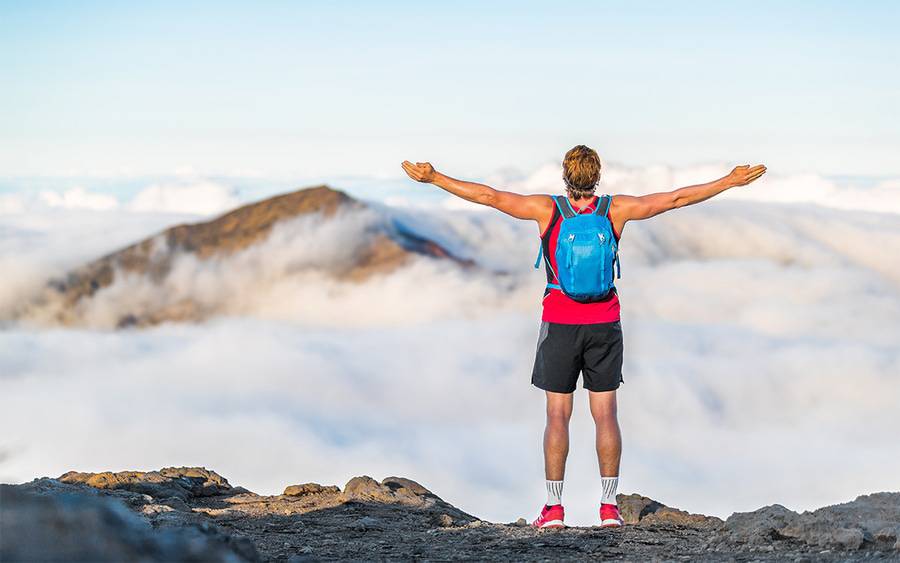 A mountain climber reaches the top of a peak and achieves his New Year's resolution to hike the tallest mountain.