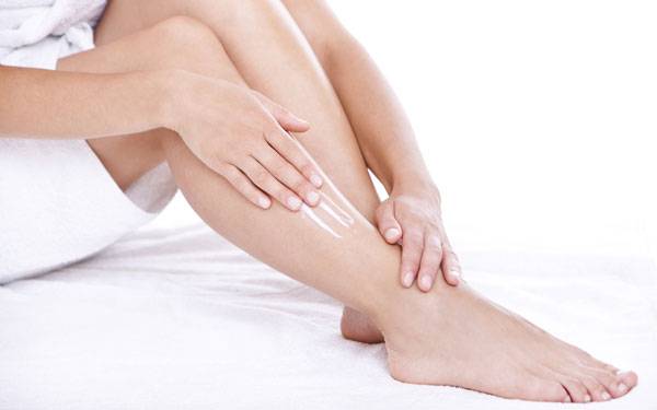 Woman applies anti-itch cream on legs.