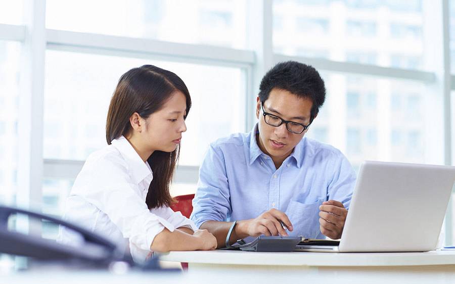 Young co-workers in an open-plan setting, which features one of the six germiest places in the office, review a project.