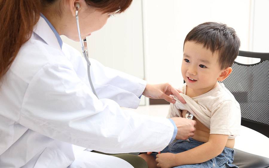 A female provider performing a routine medical exam on a child.