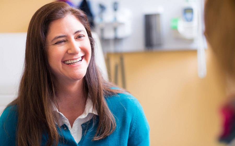 A daughter in a blue sweater smiles after realizing the importance of proactive heart health after her mother's heart attack.