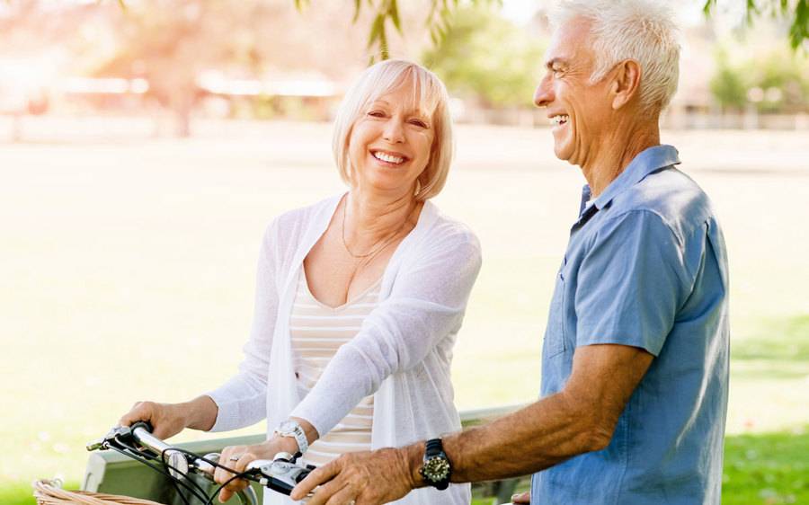A mature couple ride their bikes and share a moment of conversation about atrial fibrillation and strokes in women.