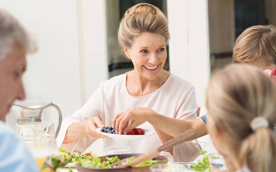 A mature woman shares a bowl of nutritious berries with her family as a way to combat bad cholesterol's impact on her health.