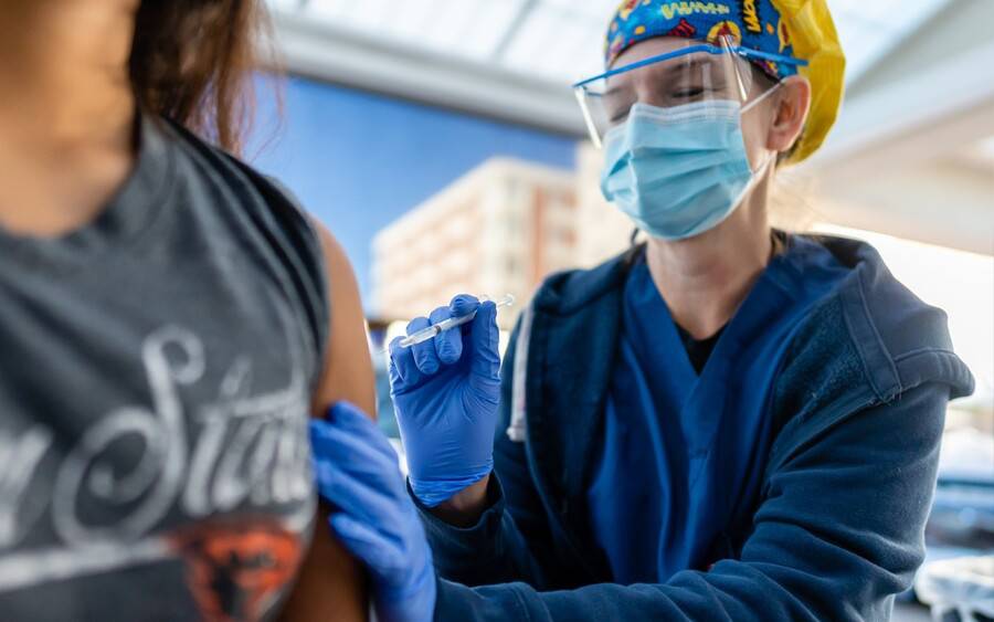 A nurse wearing protective gear administers COVID-19 vaccine to patient.