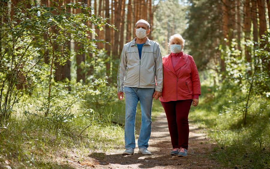 An older couple who've undertaken hiking to stay fit wear facial covering to protect from COVID-19.
