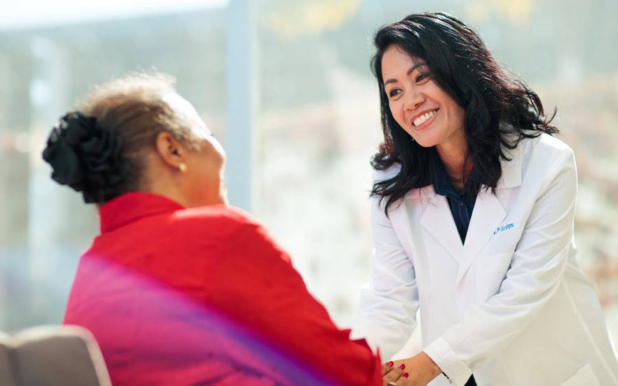 A female Scripps cancer physician smiles and bonds with a cancer patient, representing a steadfast focus on service.