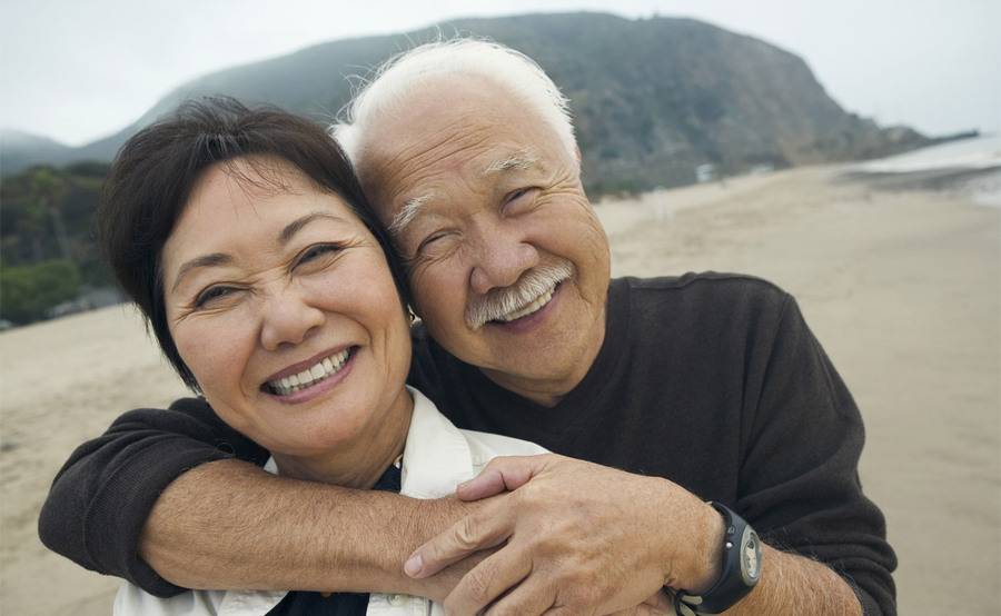 A mature couple embrace on the beach, representing an active lifestyle after hand, wrist or elbow surgery.