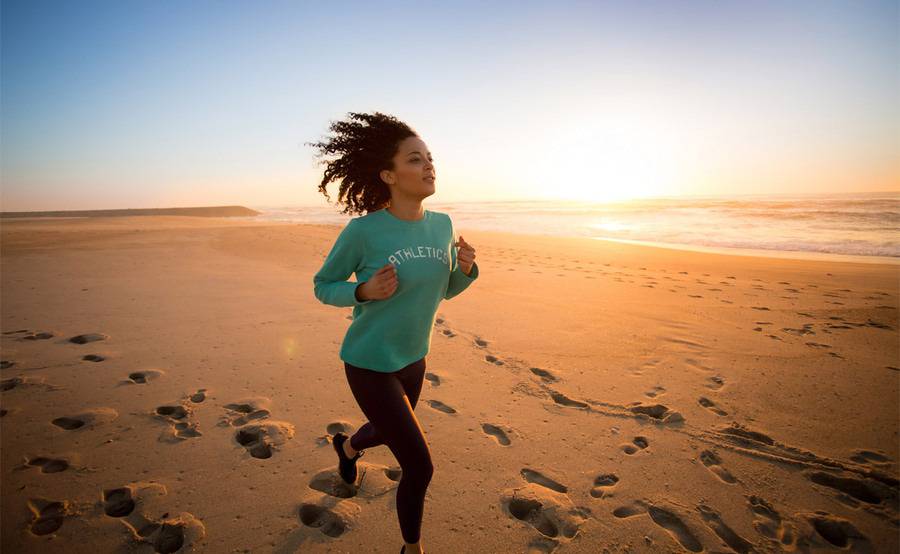A woman jogs on the beach at sunrise, representing an actively lifestyle after foot or ankle surgery.