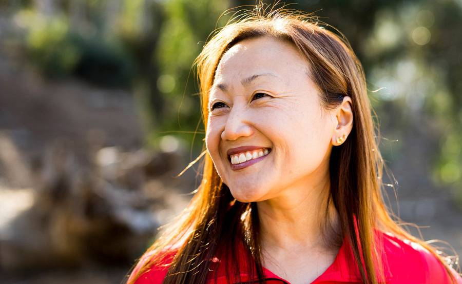 A mature Asian woman in a red zip-up represents renewed quality of life after hip replacement surgery at Scripps.