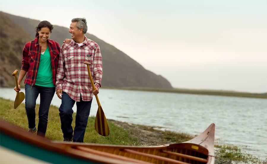 A happy couple walking outdoors to a canoe, illustrating the improvement of quality of life after knee replacement surgery.