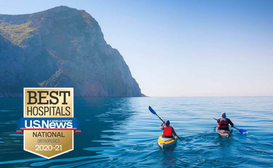 Two people paddle their kayaks around a mountain, representing an actively lifestyle after shoulder surgery.
