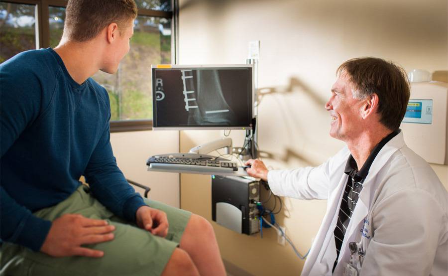 An Orthopedic Surgeon and his patient looking over some images pertaining to the young patient's ailments.