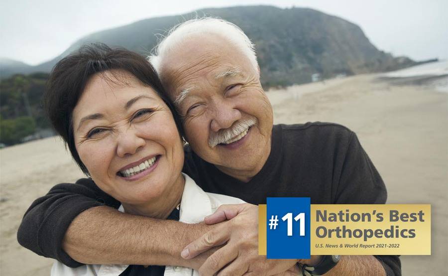 A mature couple embrace on the beach, representing an active lifestyle after hand, wrist or elbow surgery.