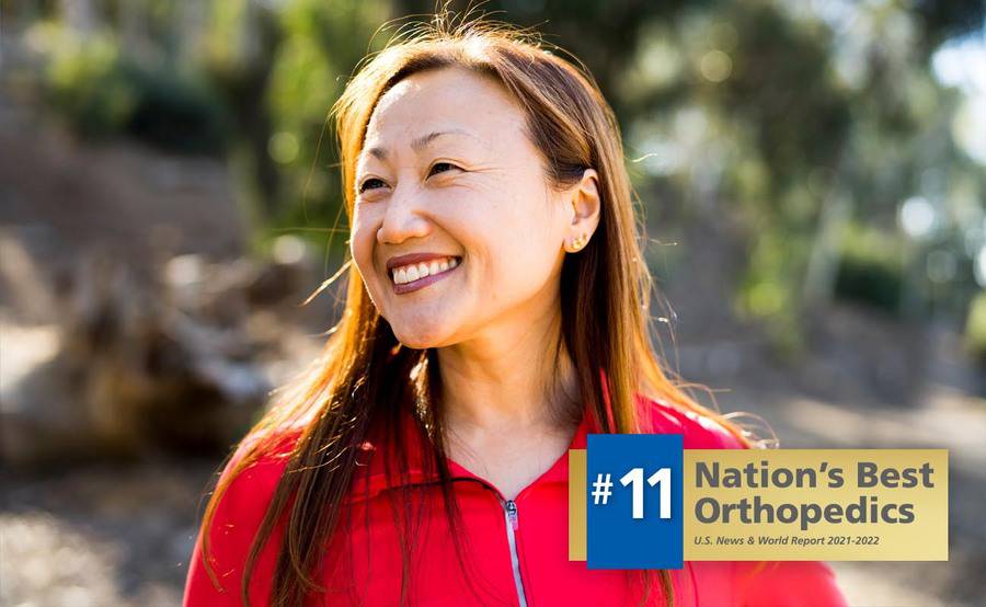A mature Asian woman in a red zip-up represents renewed quality of life after hip replacement surgery at Scripps.