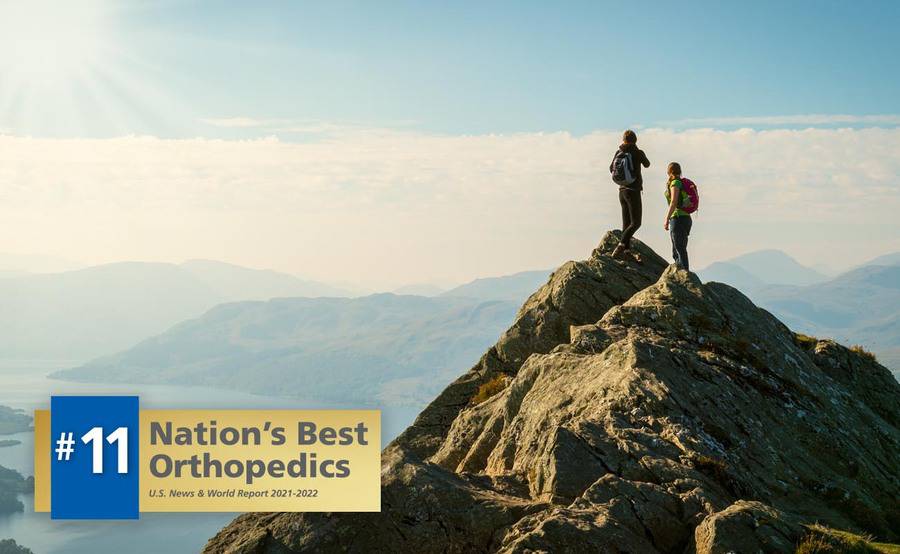 Two people stand on a mountain peak, representing an active lifestyle with expert sports medicine.
