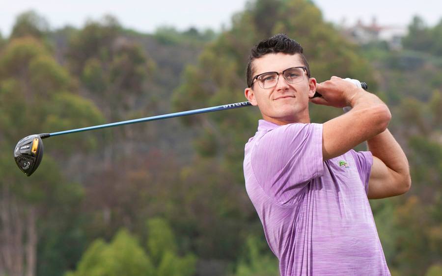 Multi-athlete, Sean O'Callaghan, wears a lavender polo and confidently swings a golf club after beating testicular cancer.