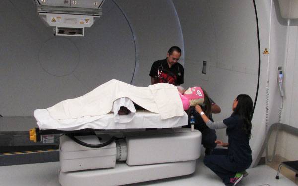 Scripps Health physician Andrew Chang helps prepare pediatric cancer patient Natalie Wright for her proton therapy treatment.