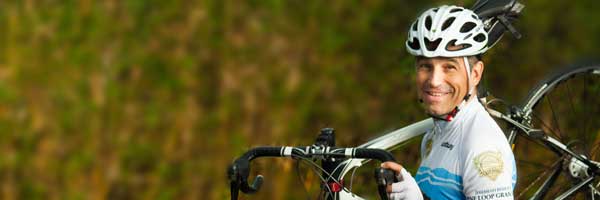 Scripps heart patient Philippe May smiling and holding a racing bicycle.