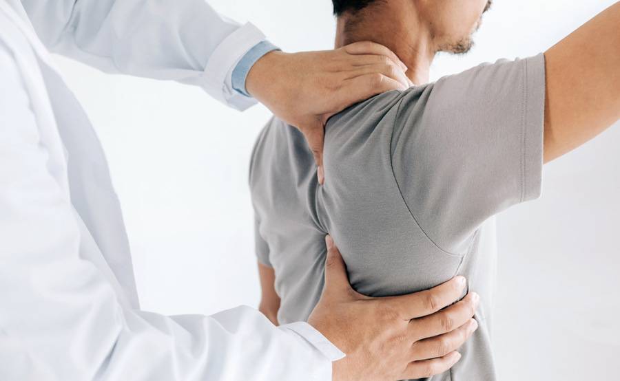 An orthopedic physician examines a patient's shoulder.