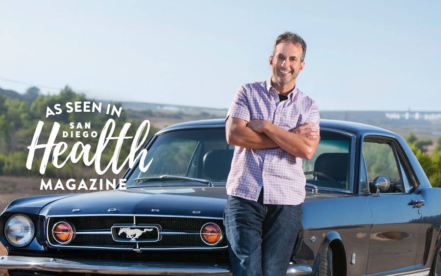 Dr. Carlos Quiros stands in front of the 1965 Mustang he rebuilt, a 30-year labor of love that has influenced how he cares for his family medicine patients.