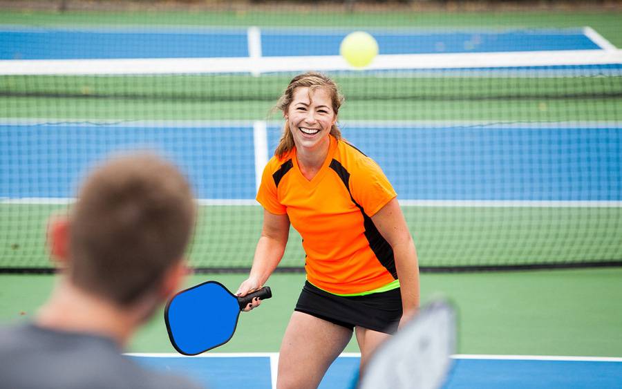 A pickleball player smiles while playing.