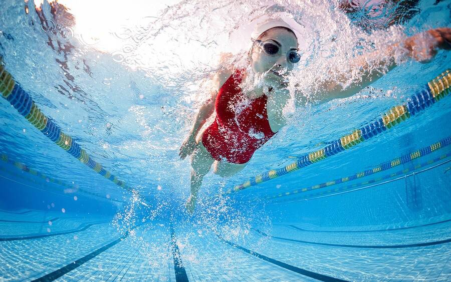 A young woman works out by swimming at recreational center.