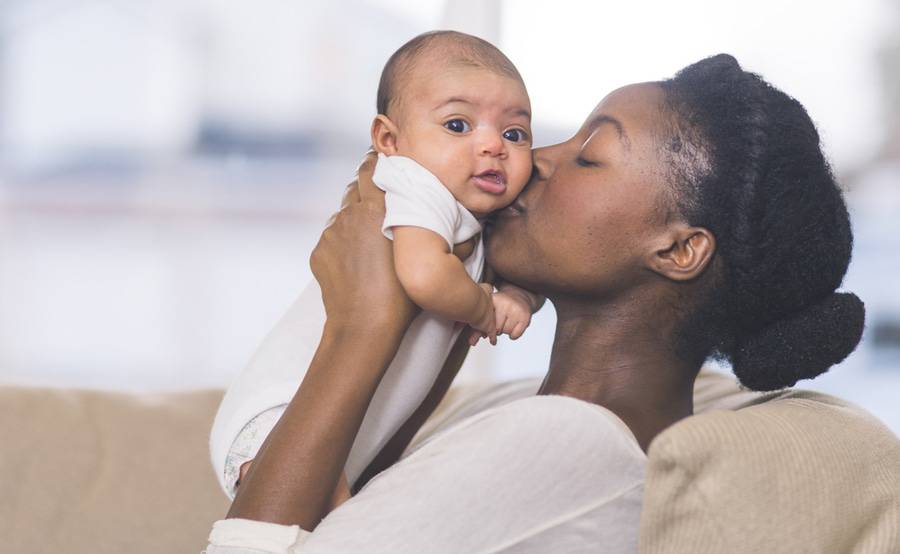 A woman holds an infant close to her face, representing healthy bonding and other aspects of parenting Scripps can help you with.