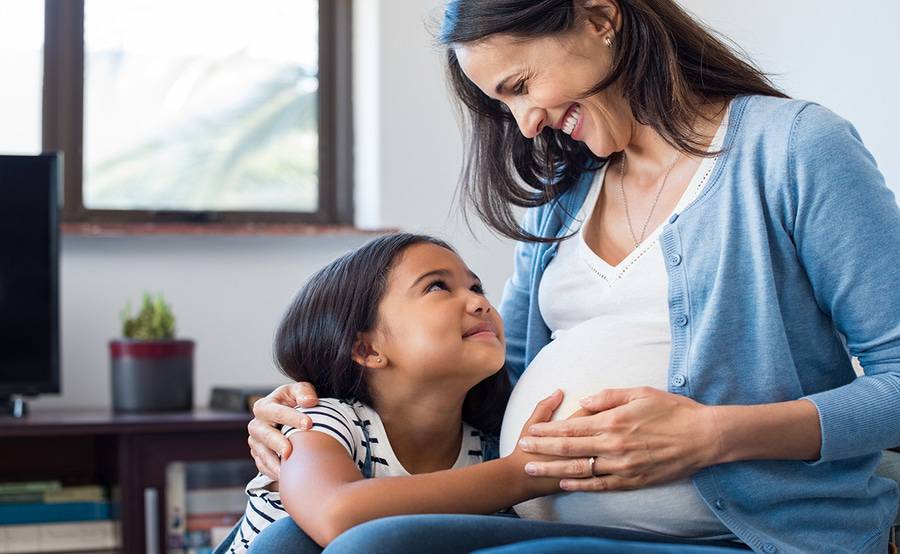A young girl touching her mother's pregnant belly represents the comforting and trusted childbirth care at Scripps Health in San Diego. 