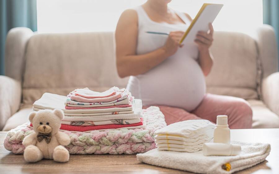 A pregnant woman sits on her couch writing her birth plan for labor and delivery.