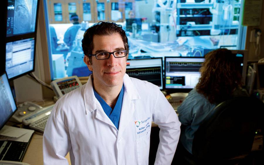Matthew Price, MD, a Scripps Clinic cardiologist stands next to the operating room where he placed his 100th mitraclip.