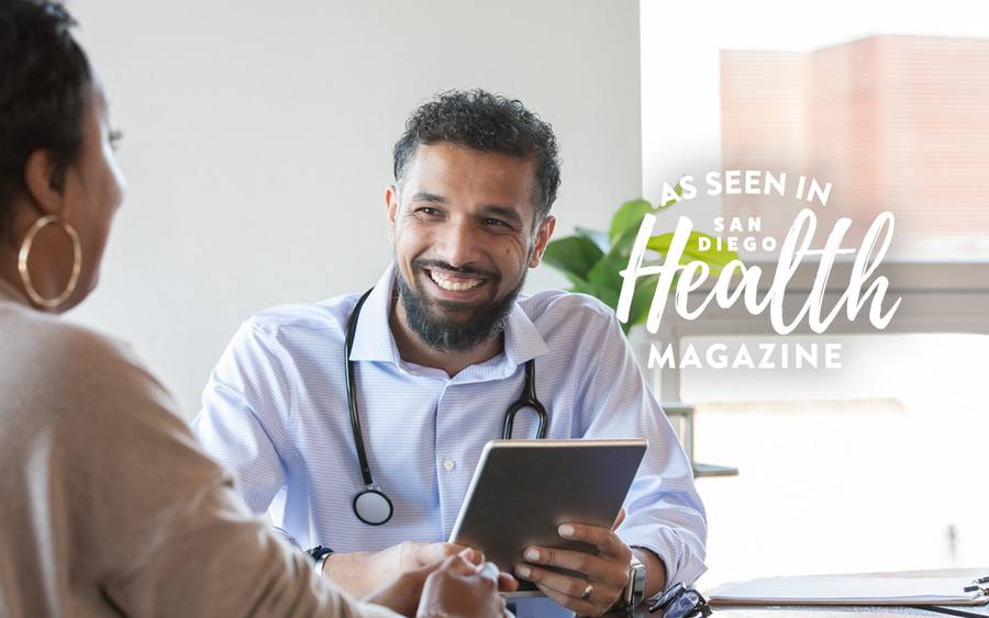 A young, male primary care physician smiles as he talks with a patient. San Diego Health Magazine
