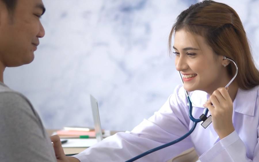 A primary care doctor conducts a health exam, checking for signs of tuberculosis.