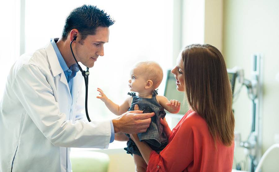 A Scripps doctor listens to the heartbeat of a baby girl held by her mother, representing the importance of finding a doctor you trust.