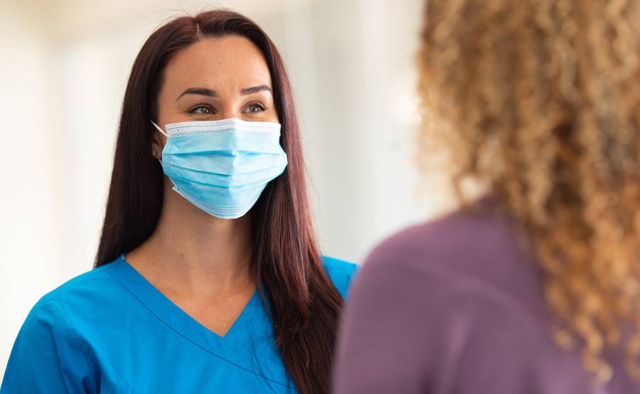 A provider with a mask on interacting with a patient.
