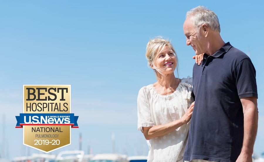 A mature couple walks along a marina, representing the healthy results of managing your respiratory disorder.