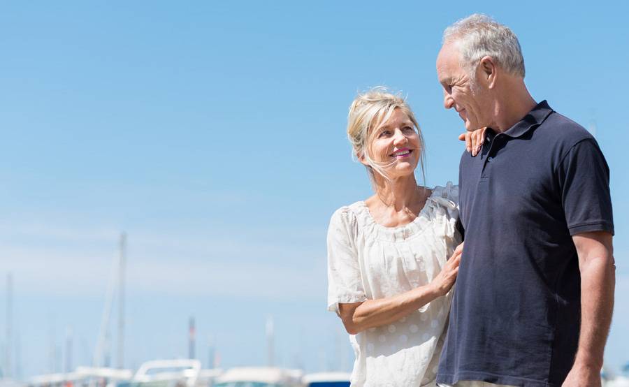 A couple walking outside on a sunny day, looking at each other and smiling.