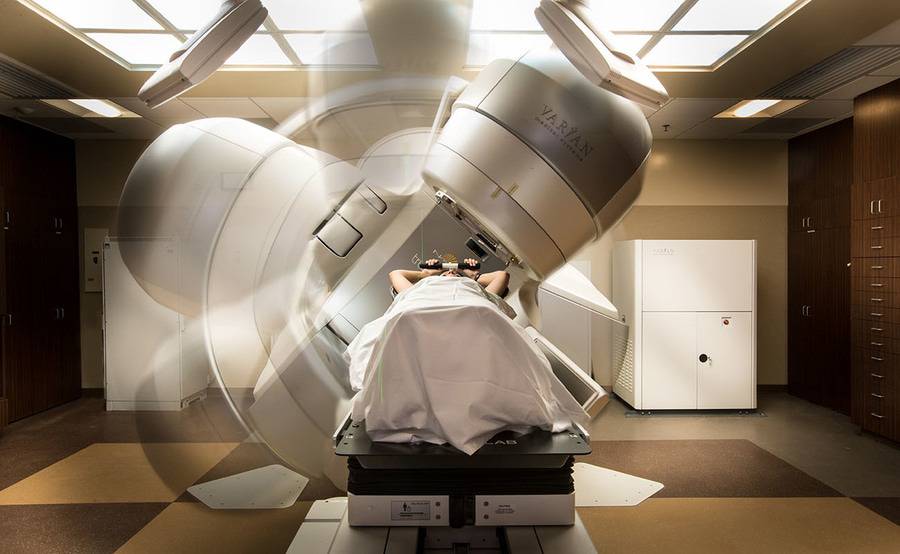 A patient comfortably lies down inside a rotating machine delivering external beam radiation therapy.