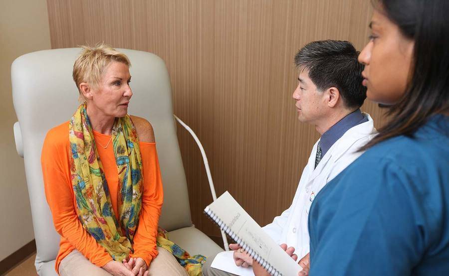 A middle-aged woman talks to a Scripps radiation oncology team, representing what happens before, during and after radiation treatment.