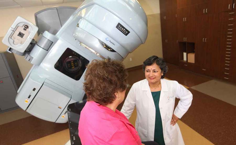 A smiling radiation oncologist talks with a cancer patient, representing the support you get from Scripps to answer your questions about radiation therapy.