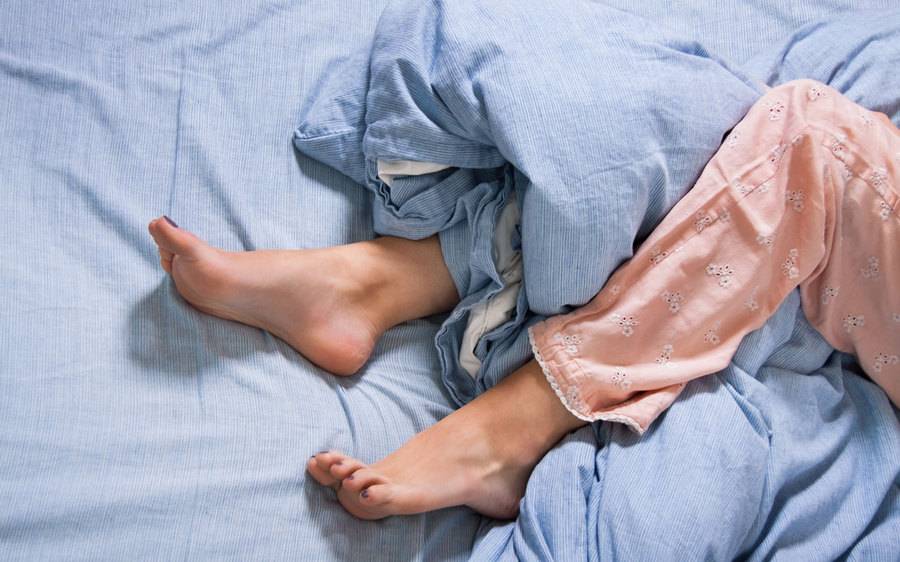 A woman laying down in bed with a focus on the legs.