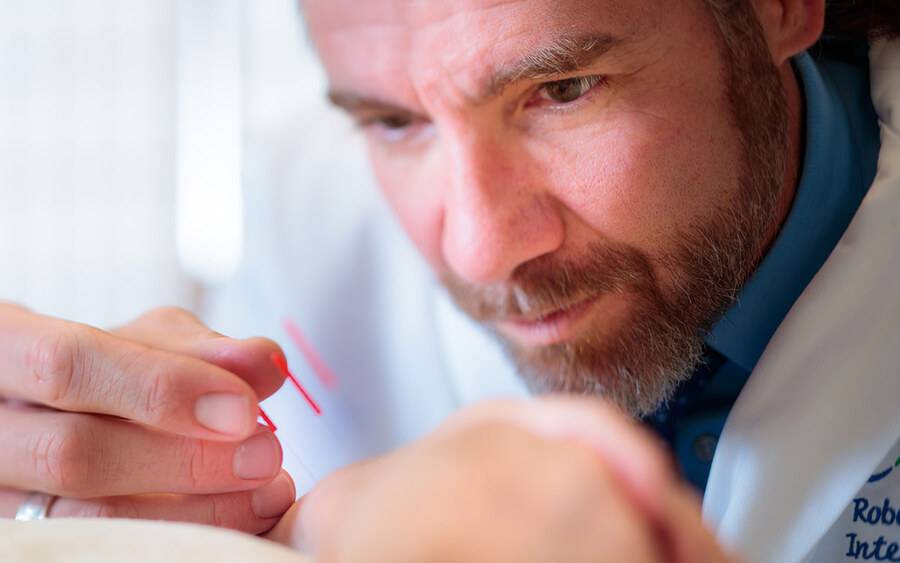 Dr. Robert Bonakdar with a patient performing acupuncture, a type of therapy that can help releive pain.