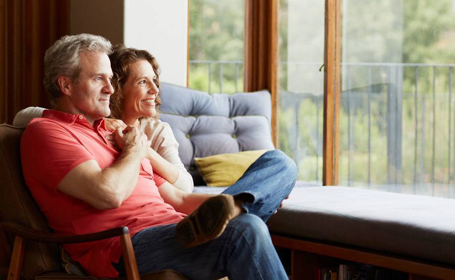 A couple holding hands as they sit together while looking out a window.