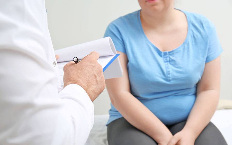 A woman sitting in a provider's office talking with provider about her care.