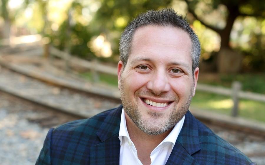 Salvatore Pacella, a Scripps doctor who co-wrote a book about facial reconstruction surgery, smiles in an outdoor setting.