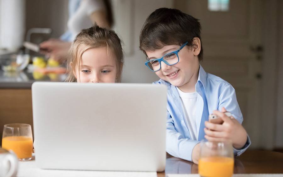 Boy and girl smile while playing video game on laptop.