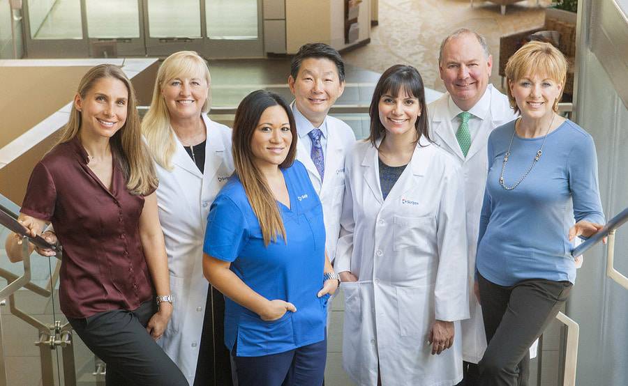 Physicians and nurses stand on a stairway as a group, representing the team of experts at Scripps Cancer Center.